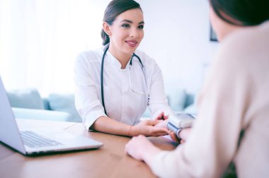 Doktor hastanedeki hastaya kan basıncını ölçüyor.