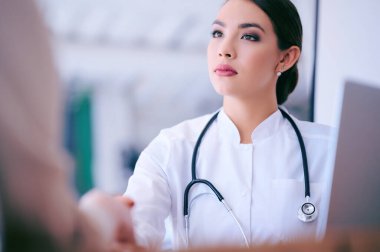 Bayan doktor hastayla ofiste tokalaşıyor. Yüksek kalite fotoğraf