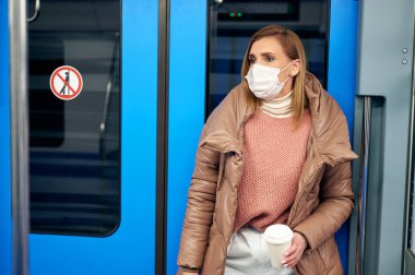 Metro istasyonundaki koruyucu cerrahi maske takan kadın koronavirüs riskini önlüyor.