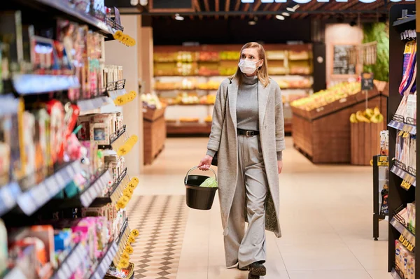 2020-12-22, Minsk, Belarus. Tıbbi maskeli kadın virüs salgını sırasında marketten alışveriş yapıyor.