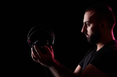 Genç sakallı Arap DJ müzisyen kulaklıkları elinde tutuyor. Uluslararası DJ Günü