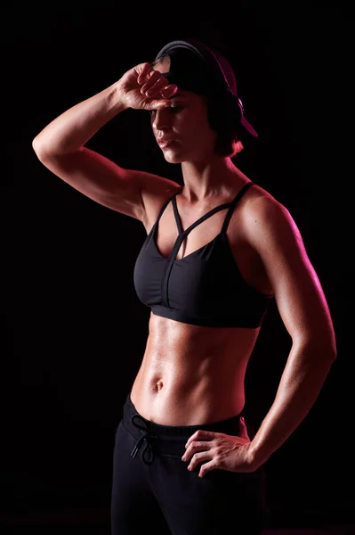 Caucasian slim strong woman with muscular body and perfect abdomen with headphones on black isolated background — Stock Photo, Image