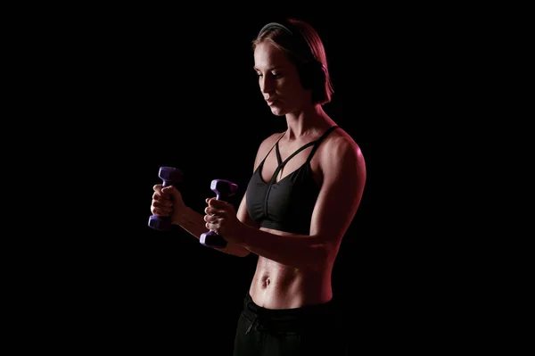 Mladá silná žena s perfektní břicho a silné paže cvičení s činky na černém pozadí — Stock fotografie