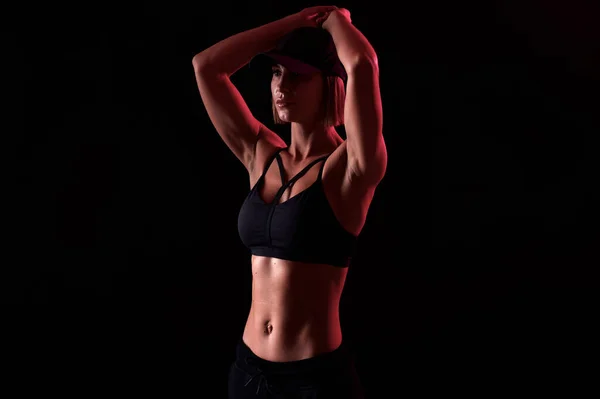 Starke Frau in Sport-BH mit muskulösem Bauch vor schwarzem Hintergrund. Perfekte Körperform — Stockfoto