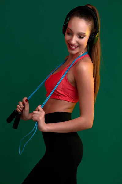 Štíhlá krásná sportovní žena s skákacím lanem poslech hudby ve sluchátkách — Stock fotografie