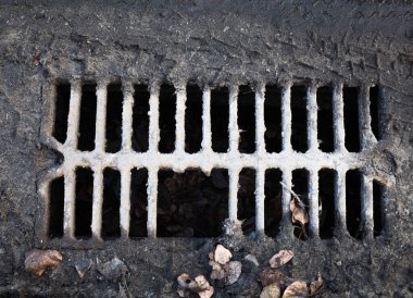 Çamurla kaplı kırık metal akış ızgarası. Yakın plan..