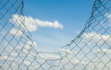 Kırık metal tel örgüler mavi gökyüzüne karşı. 