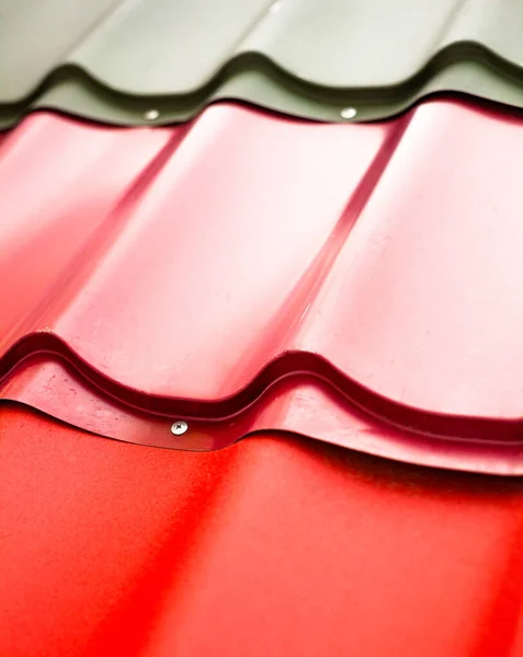 Metal roofing tiles Red, pink and black tiles. Roof covering material. Close-up.