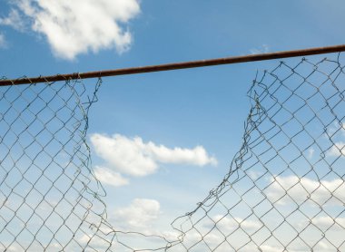 Kırık metal tel örgüler mavi gökyüzüne karşı. 
