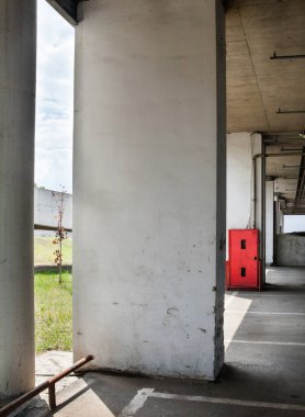 Binanın altına park etmek (otopark altı). Beton kolonlar. Kırmızı yangın güvenlik dolabı.