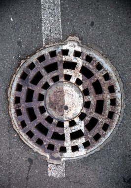Asfaltta metal kaplı, beyaz yol işaretli rögar deliği.