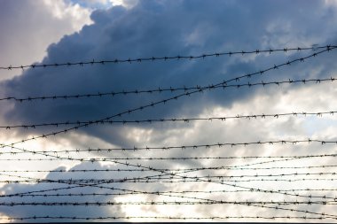 Bulutlu gökyüzü arkaplanına dikenli tel