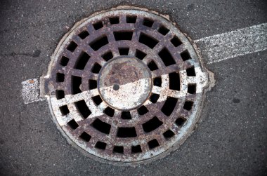 Asfaltta metal kaplı, beyaz yol işaretli rögar deliği.