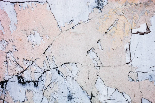 Cracked concrete surface with the remains of sandy-tan paint