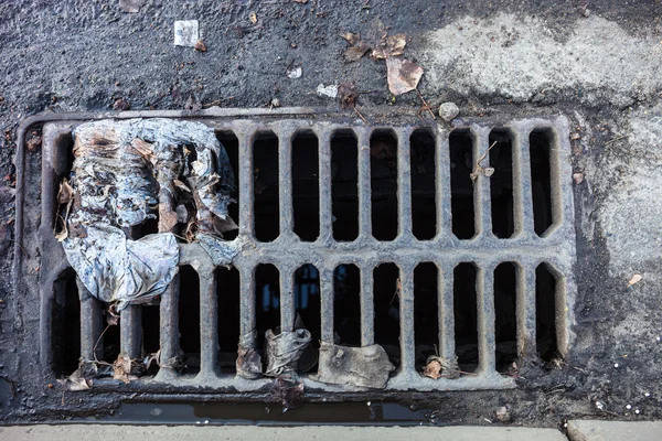 Drain grate with the garbage — Stock Photo, Image