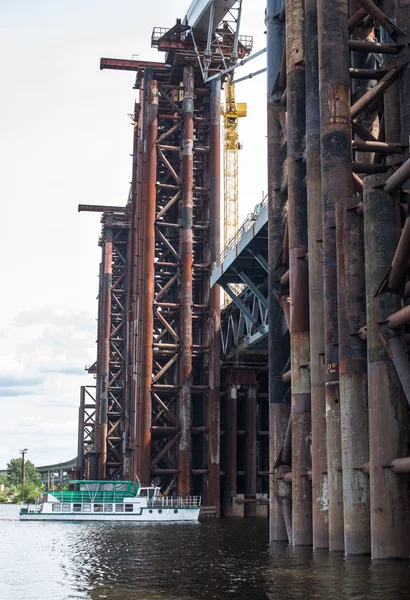 The boat floating under the unfinished bridge construction — Stock Photo, Image