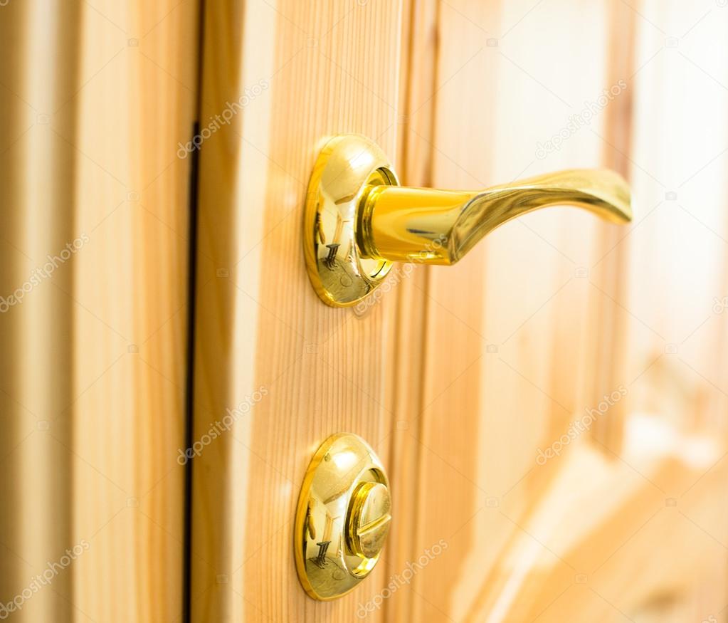 Golden door handle and lock on the wooden door