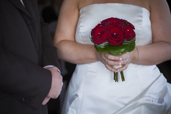 Bride and groom with red roses bouquet — Stock fotografie