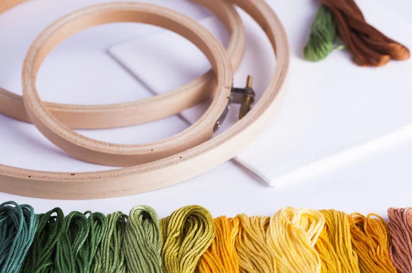 Embroidery yarns and hoops on fabric background — Stock Photo, Image
