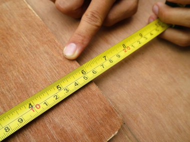 Çekilebilir mezura tutan bir el. Ölçeği açıkça 15 cm 'nin ölçüsünü gösteriyor.