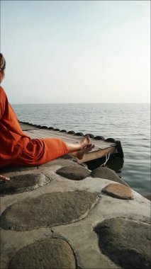 Turuncu gömlekli kadın bulutlu bir günde sakin su sahiline bakan Stoney Rıhtımı 'nda oturuyor, iyileşmek için seyahat ediyor.