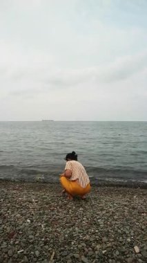 Okyanus esintisini sakin bir plajda kucaklayan Asyalı kadın zihinsel sağlık farkındalığı, tropikal turizm broşürleri ve yaşam tarzı bloglarında kullanmak üzere kişisel iyileşme ve solo seyahat anı yakalıyor.