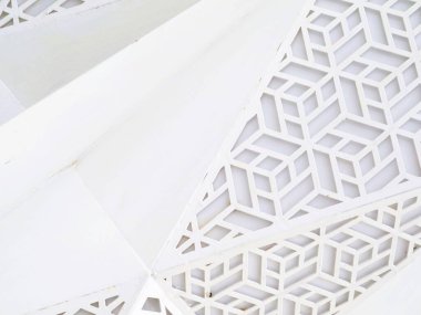 Bir binanın ön cephesinde geometrik desenli beyaz mimari detayların yakın görüntüsü, geometrik desenler