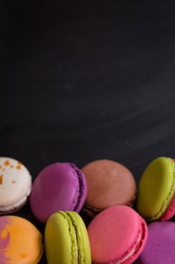 Karanlık bir arka plan üzerinde çeşitli renkli macaroons