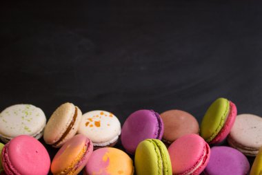 Karanlık bir arka plan üzerinde çeşitli renkli macaroons