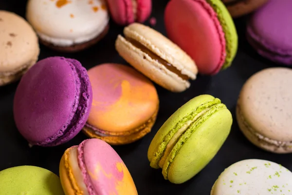 Macaroons coloridos variados em um fundo escuro — Fotografia de Stock