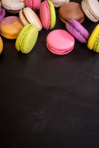 Macaroons coloridos variados em um fundo escuro — Fotografia de Stock