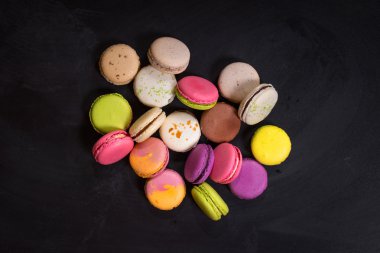 Karanlık bir arka plan üzerinde çeşitli renkli macaroons
