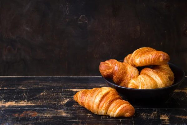 Croissants in a black bowl on the dark background