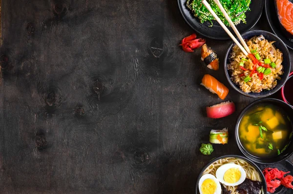 Sushi y comida japonesa sobre fondo oscuro — Foto de Stock