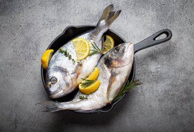 Çiğ balık çipurası veya yukarıdan gelen dökme demir tavada dorado.