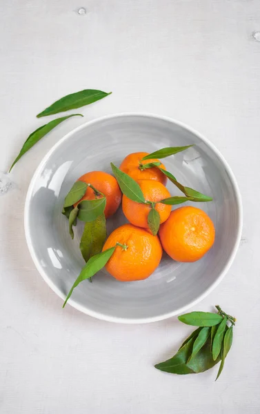 Tangeriner med gröna blad på vit trä bakgrund — Stockfoto