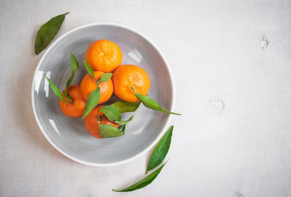 Tangeriner med gröna blad på vit trä bakgrund — Stockfoto