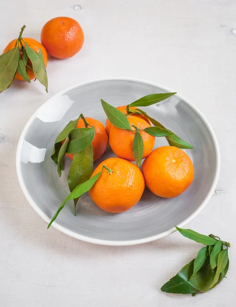 Mandarinas con hojas verdes sobre fondo de madera blanca Fotos de stock