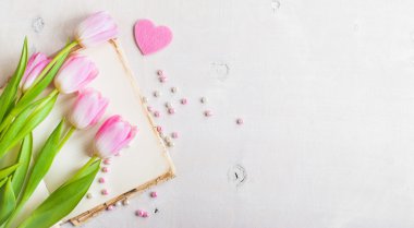 Kalp ve boncuk Beyaz ahşap masa üzerinde pembe laleler