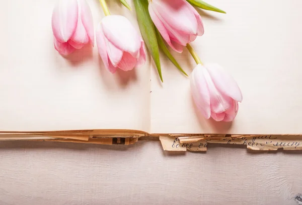 Tulipanes rosados y libro en blanco sobre mesa de madera blanca. Espacio libre f — Foto de Stock