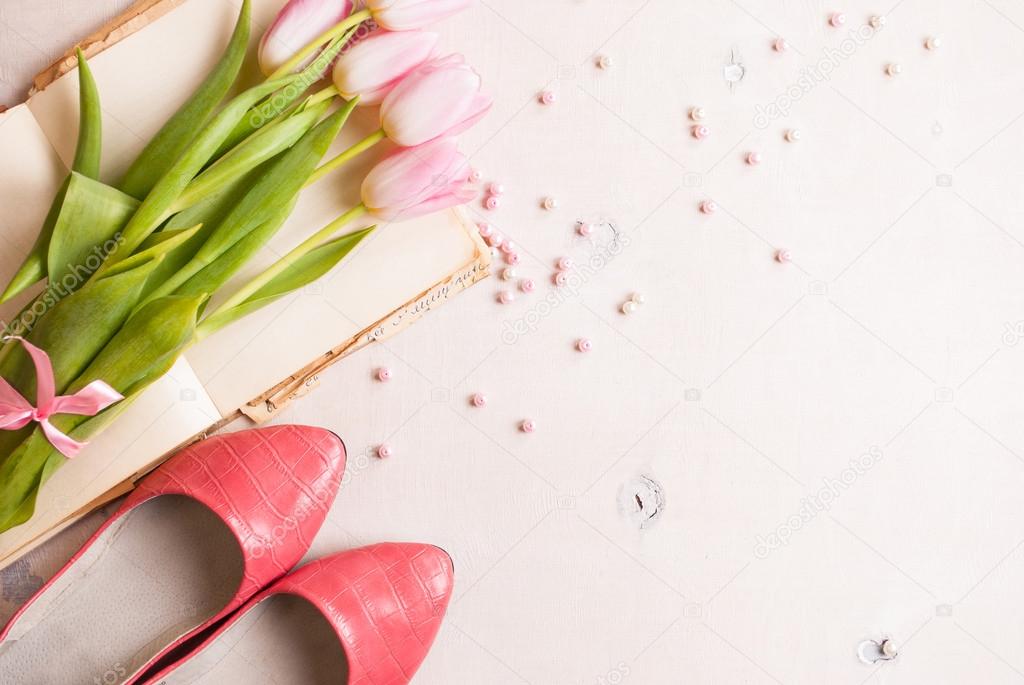 Pink tulips with womens shoes over white wooden table. Spring c