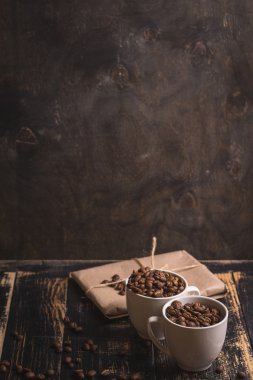 Fincan kahve çekirdekleri, koyu ahşap arka plan ile