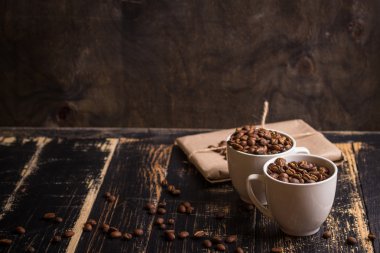 Fincan kahve çekirdekleri, koyu ahşap arka plan ile