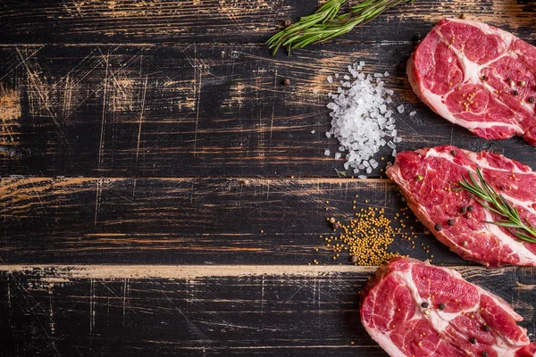 Bife de carne crua no fundo de madeira escura pronto para assar — Fotografia de Stock