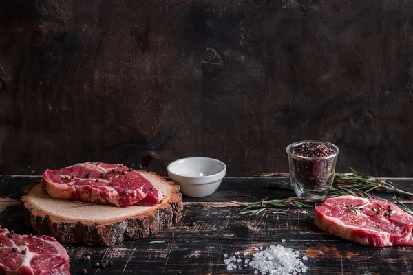 Bifteck de viande cru juteux sur fond de bois foncé prêt à rôtir — Photo