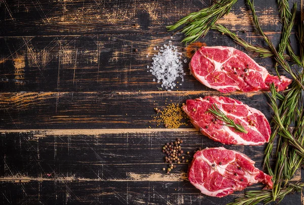 Steak de viande crue sur fond de bois foncé prêt à rôtir — Photo