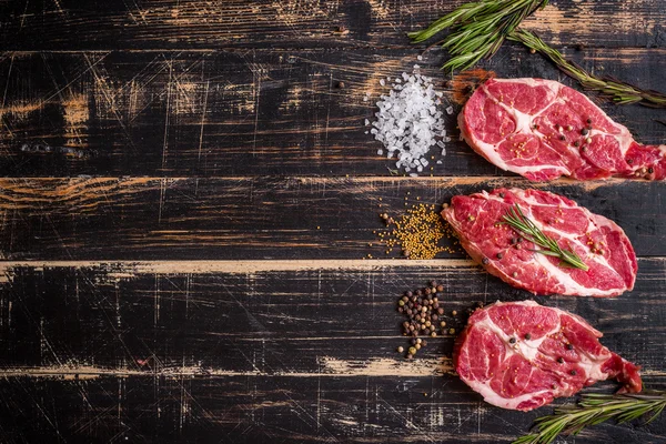 Bistecca di carne cruda su fondo di legno scuro pronta per essere arrostita — Foto Stock