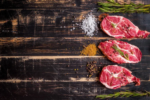 Rauw vlees biefstuk op donkere houten achtergrond klaar om te roosteren — Stockfoto