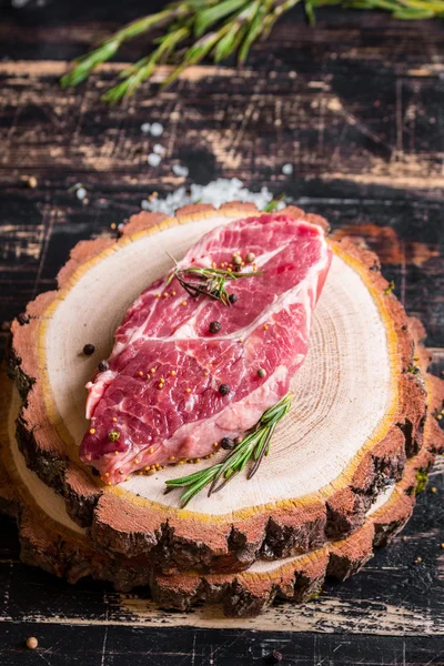 Bife de carne suculento cru no fundo de madeira escura pronto para assar — Fotografia de Stock