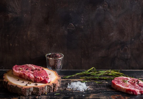 Bifteck de viande cru juteux sur fond de bois foncé prêt à rôtir — Photo